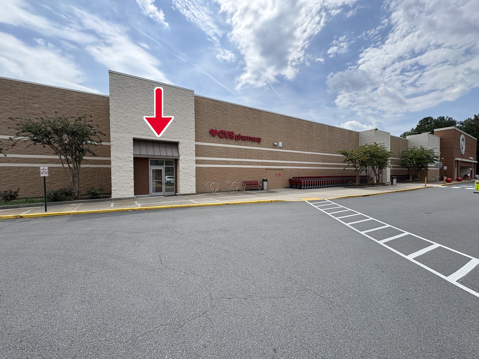 Our entrance — the glass door under the white tower, to the left of Target. A red arrow marks the door.